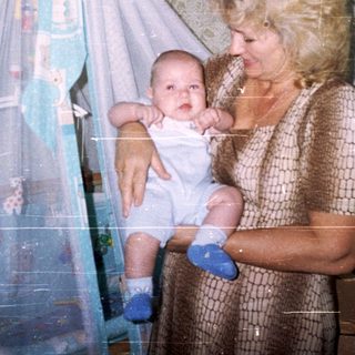 Woman holding a baby in a bedroom with a playpen.