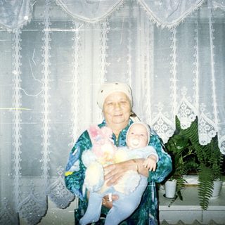 Elderly woman holding a baby in a traditional outfit.