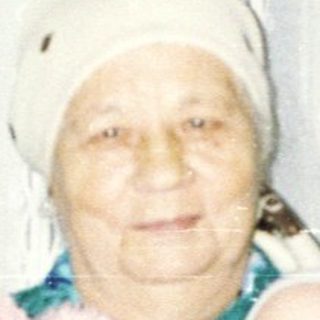 Elderly woman holding a baby in a traditional outfit.
