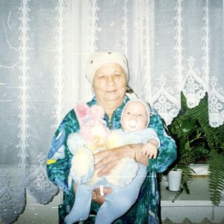 Elderly woman holding a baby in a traditional outfit.