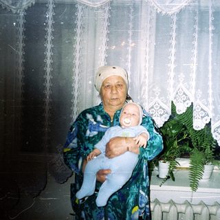 Older woman holds baby in a home setting.