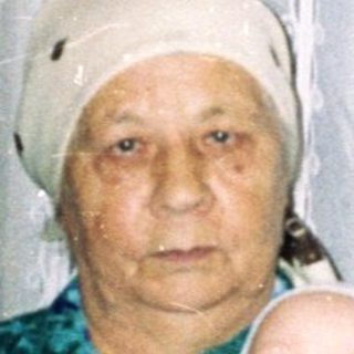 Older woman holds baby in a home setting.