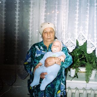 Older woman holds baby in a home setting.