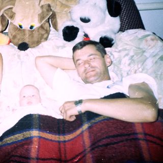 Men and baby sleep under large stuffed animals.
