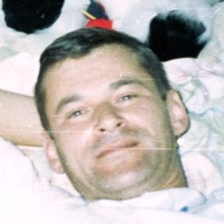Men and a baby relax on a bed with toys.