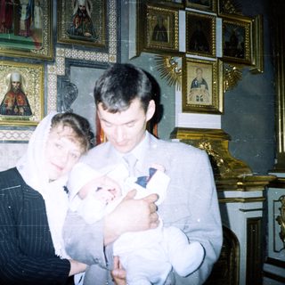 Couple holds baby in a church setting.