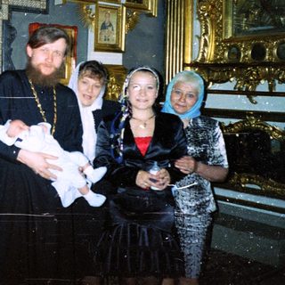 Group gathers for a baby's baptism in a church.