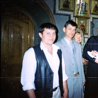 Group gathers for a baby's baptism in a church.