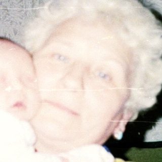 Elderly woman holding a newborn baby indoors.
