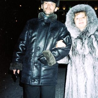 Couple stands outdoors in winter clothing, appearing stylish.