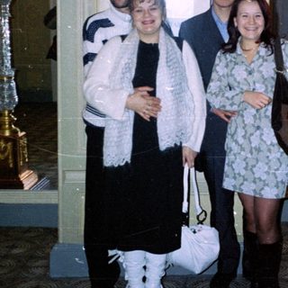Four people pose indoors near ornate, decorative candelabras.