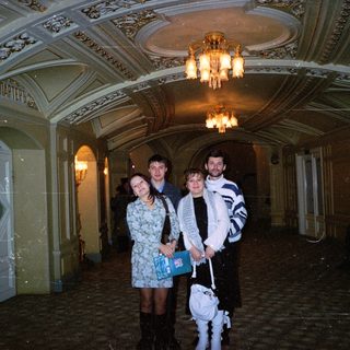 Three people stand in a grand, ornate hallway.