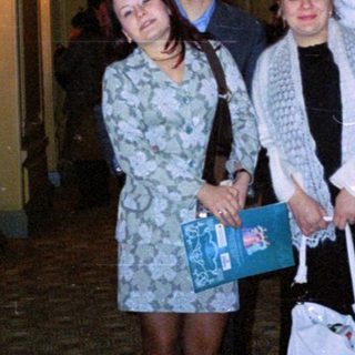 Three people stand in a grand, ornate hallway.