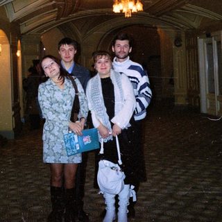 Three people stand in a grand, ornate hallway.