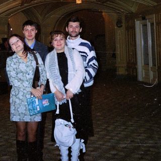 Three people stand in a grand, ornate hallway.
