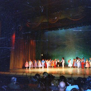 Performers on stage in a theater with an audience.