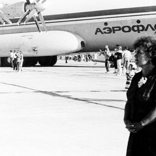 Crowd gathers near a Soviet-era airplane on an airfield.