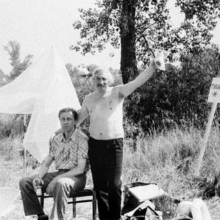 Two men in an outdoor setting with a sign.