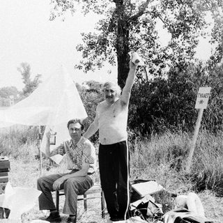 Men sit and stand outdoors with film equipment.