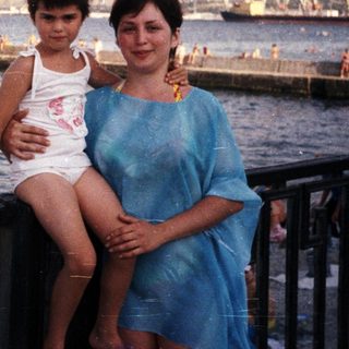 Mother and child pose by the seaside with a view.