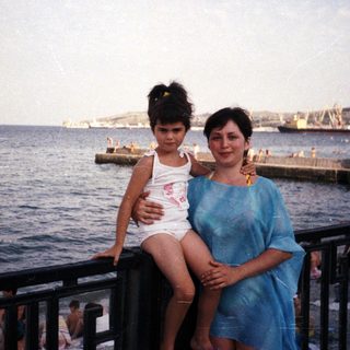Mother and child pose by the seaside with a view.