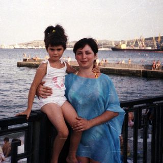 Mother and child pose by the seaside with a view.