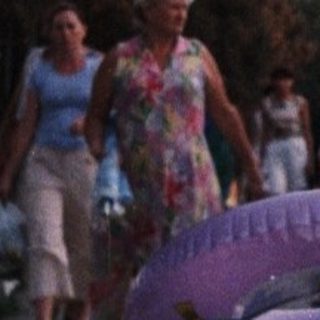 Girl stands on road with group of people nearby.