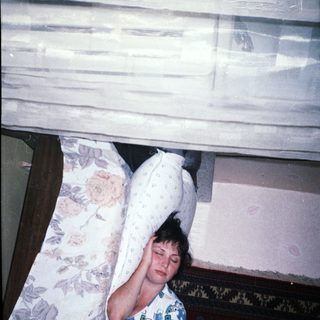 Here's a brief summary: Woman lying on a bed, partially visible in a room.