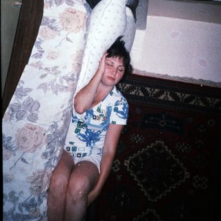 Here's a brief summary: Woman lying on a bed, partially visible in a room.