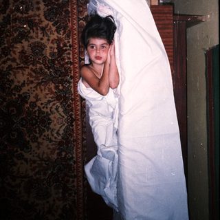 Here's a brief summary: Girl lies on a bed with a patterned rug.