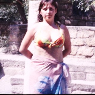 Woman stands near stone structure, partially covered with a cloth.