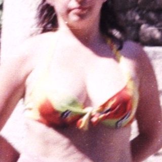 Woman stands near stone structure, partially covered with a cloth.