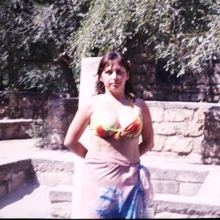 Woman stands near stone structure, partially covered with a cloth.