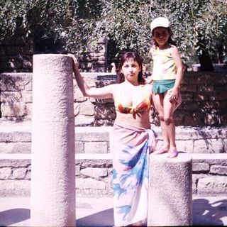 Woman and child posing near ancient stone ruins.