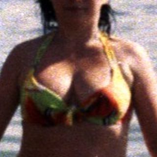 Woman stands in water, holding a child on a float.