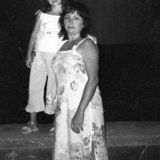 Woman and child stand outside at night, illuminated.