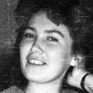 Young woman smiling, seated in a vintage train car.