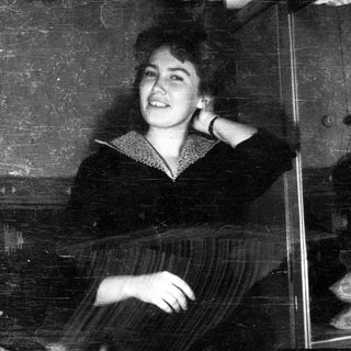 Young woman smiling, seated in a vintage train car.
