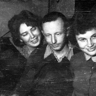 Here's a brief summary: Three people smiling for a vintage black and white portrait.