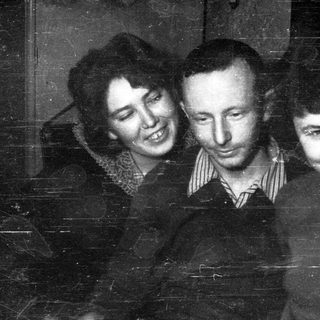 Here's a brief summary: Three people smiling for a vintage black and white portrait.