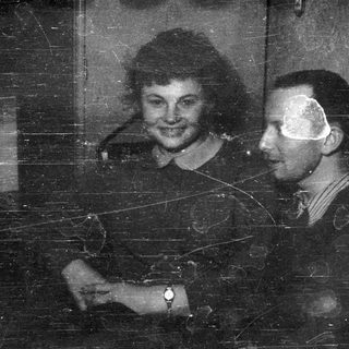 Here's a brief summary of the image: A smiling woman and a man in profile are pictured.