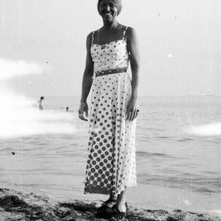Woman in a dress stands on a beach.