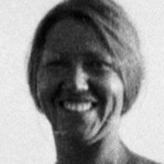 Woman in a dress stands on a beach.