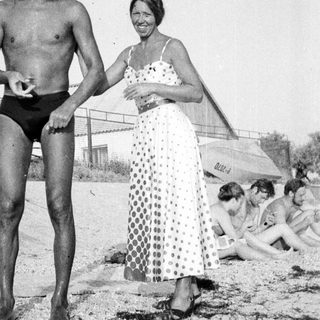 Man and woman on a beach, people in background.