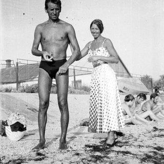 Man and woman on a beach, people in background.