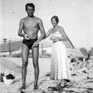 Man and woman on a beach, people in background.