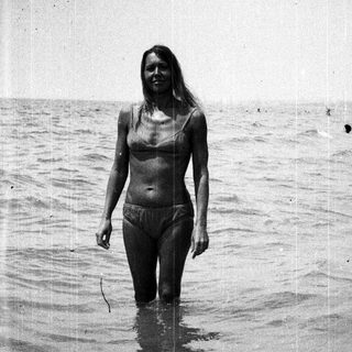 Woman standing in water, wearing a bikini.
