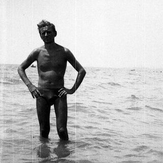 Man stands in shallow water, looking toward the horizon.