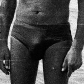 Man and boy standing in shallow water by the sea.