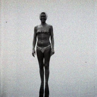 Woman stands in water, reflected in a grayscale image.